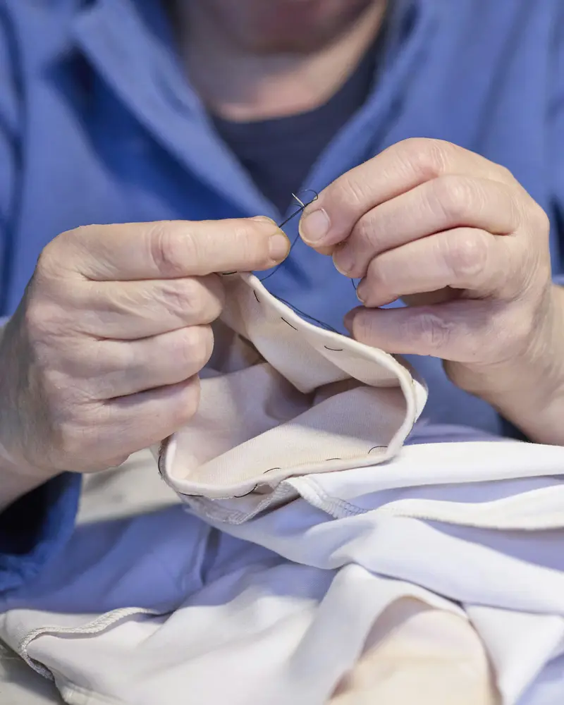 A person mending a white shirt by hand