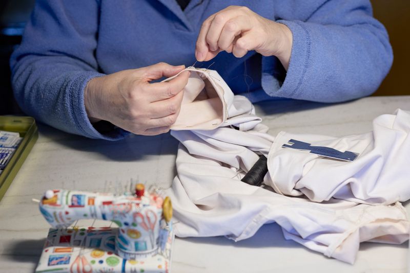 Master tailor hand-sewing a garment with needle and thread